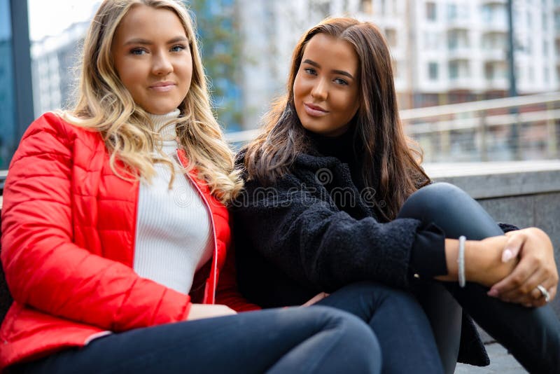 Portret Dwa Uśmiechniętego Żeńskiego przyjaciela Siedzi W mieście fotografia royalty free Portret Dwa Uśmiechniętego Żeńskiego przyjaciela Siedzi W mieście fotografia royalty free