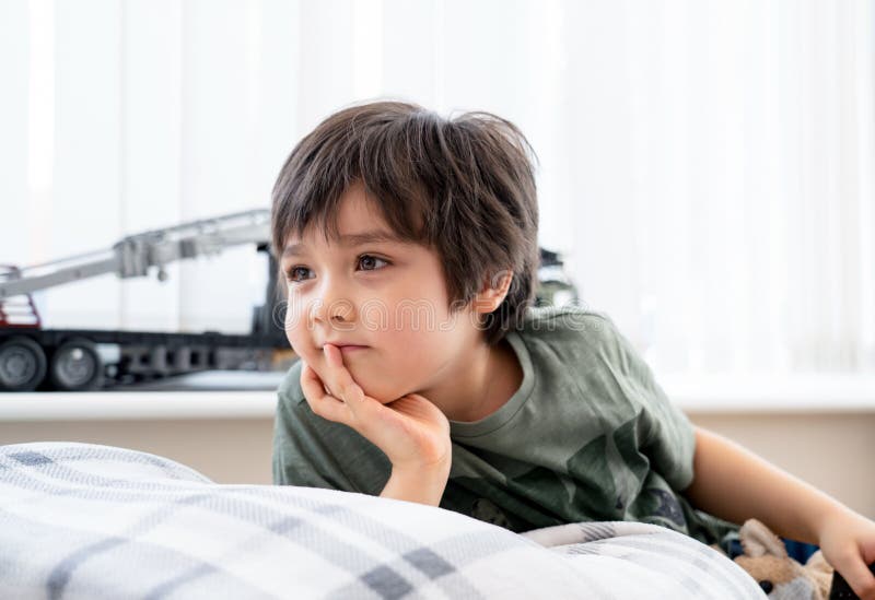 Portrait healthy kid ying on sofa watching TV in living room, Child boy with happy face relaxing at home in sunny day spring or summer, Positive children concept. Portrait healthy kid ying on sofa watching TV in living room, Child boy with happy face relaxing at home in sunny day spring or summer, Positive children concept