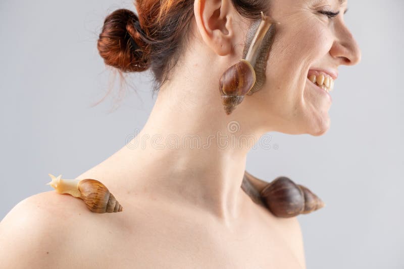 Portret kaukaskiej kobiety z ślimakami na twarzy. wykorzystania skorupiaków w kosmetologii. zdjęcie stock