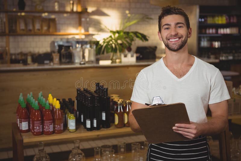Portret kelnera mienia schowek przy kawiarnią obrazy stock Portret kelnera mienia schowek przy kawiarnią obrazy stock