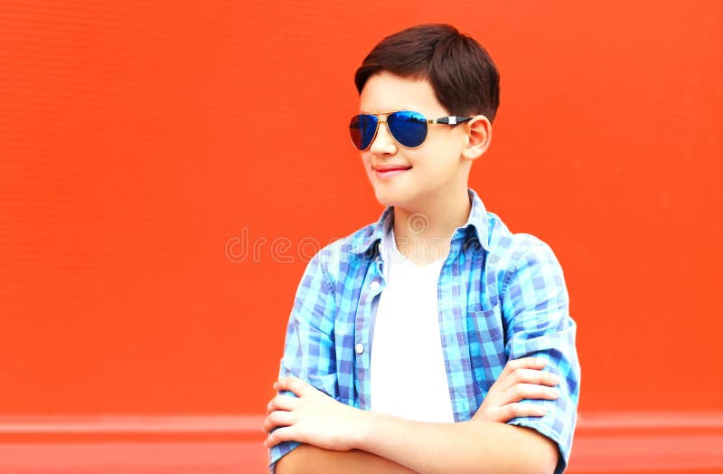 Portret mody dziecka chłopiec w okulary przeciwsłoneczni na kolorowej czerwieni zdjęcie stock Portret mody dziecka chłopiec w okulary przeciwsłoneczni na kolorowej czerwieni zdjęcie stock