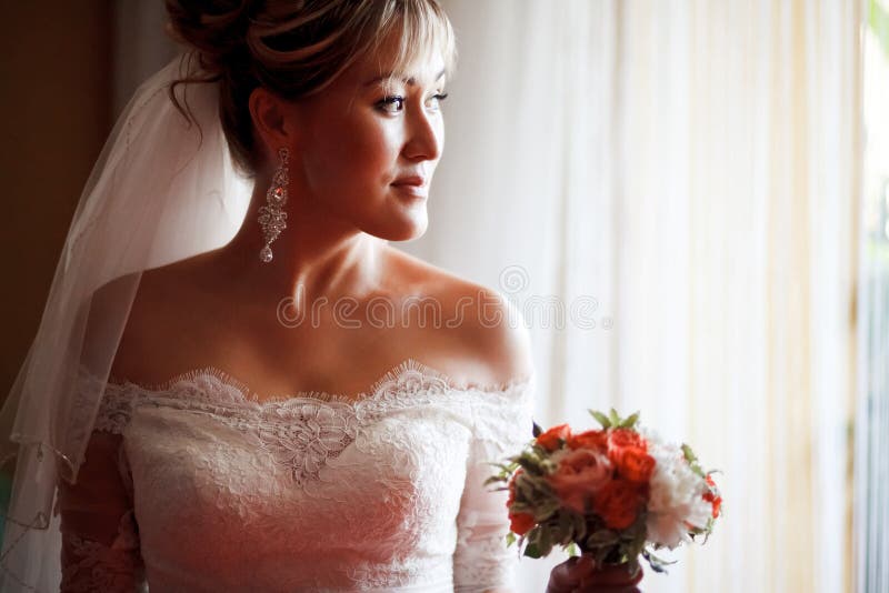 Portret panna młoda w profilu z ślubnym bukietem obok okno fotografia royalty free Portret panna młoda w profilu z ślubnym bukietem obok okno fotografia royalty free