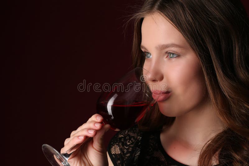 Portrait of girl drinking wine, girl with wineglass, high fashion look, beautiful girl, brunette girl, isolated, model in studio, long hair, close up, dark red background. Portrait of girl drinking wine, girl with wineglass, high fashion look, beautiful girl, brunette girl, isolated, model in studio, long hair, close up, dark red background