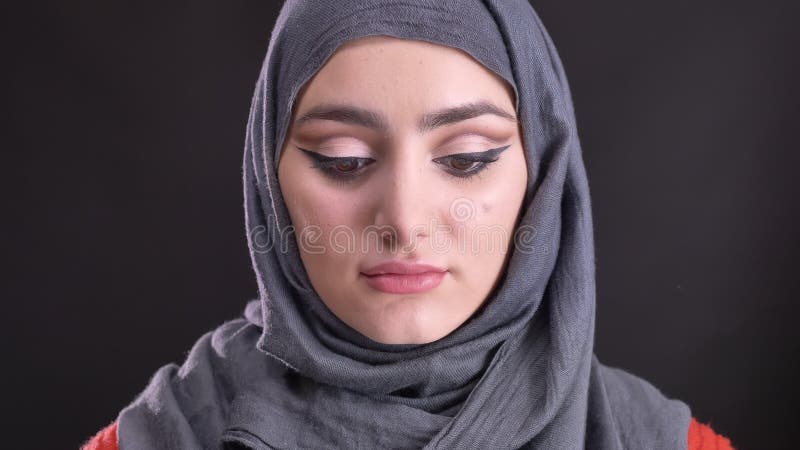 Portret piękna muzułmańska kobieta w hijab z modnymi makijaży zegarkami skromnie w kamerę na czarnym tle