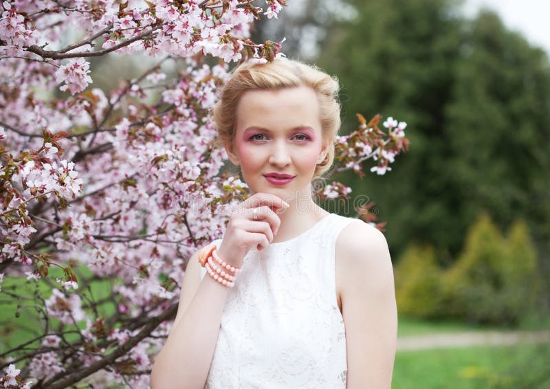 Portret piękna młoda blond kobieta na tle różowi czereśniowi okwitnięcia w wiośnie fotografia stock Portret piękna młoda blond kobieta na tle różowi czereśniowi okwitnięcia w wiośnie fotografia stock