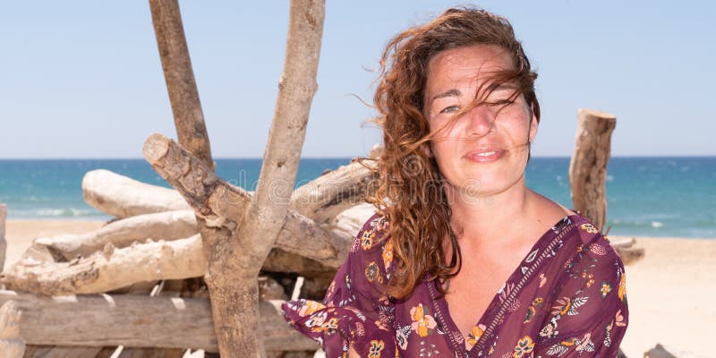 Portret piękna 40 roczniaka brunetki kobieta na lato piaska plaży driftwood w szablon sieci sztandarze fotografia stock