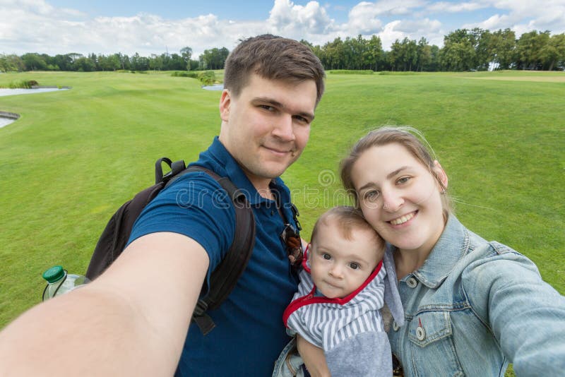 Portret piękna szczęśliwa rodzina z dzieckiem robi selfie przy pa zdjęcia stock Portret piękna szczęśliwa rodzina z dzieckiem robi selfie przy pa zdjęcia stock