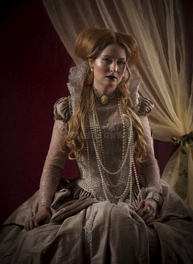 Color portrait of beautiful red haired woman dressed in period costume with Elizabethan collar, pearl jewelry and dress, to resemble historical figure, Queen Elizabeth I of England, shot in warm hues. Color portrait of beautiful red haired woman dressed in period costume with Elizabethan collar, pearl jewelry and dress, to resemble historical figure, Queen Elizabeth I of England, shot in warm hues.