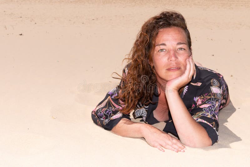 Portret pięknej 40-letniej brunetki leżącej na plaży piaskowej zdjęcia stock