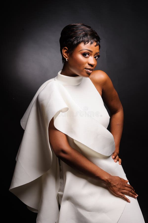 Portrait of a beautiful young African woman in white dress over black background. Studio picture, adult, afro, american, attractive, beauty, brown, casual, color, concept, confident, cute, ethnicity, expression, face, fashionable, female, girl, hair, hairstyle, hand, happy, head, idea, indoor, , lifestyle, looking, makeup, nice, one, people, person, posing, pretty, shot, shoulders, smile, student, women, yellow. Portrait of a beautiful young African woman in white dress over black background. Studio picture, adult, afro, american, attractive, beauty, brown, casual, color, concept, confident, cute, ethnicity, expression, face, fashionable, female, girl, hair, hairstyle, hand, happy, head, idea, indoor, , lifestyle, looking, makeup, nice, one, people, person, posing, pretty, shot, shoulders, smile, student, women, yellow