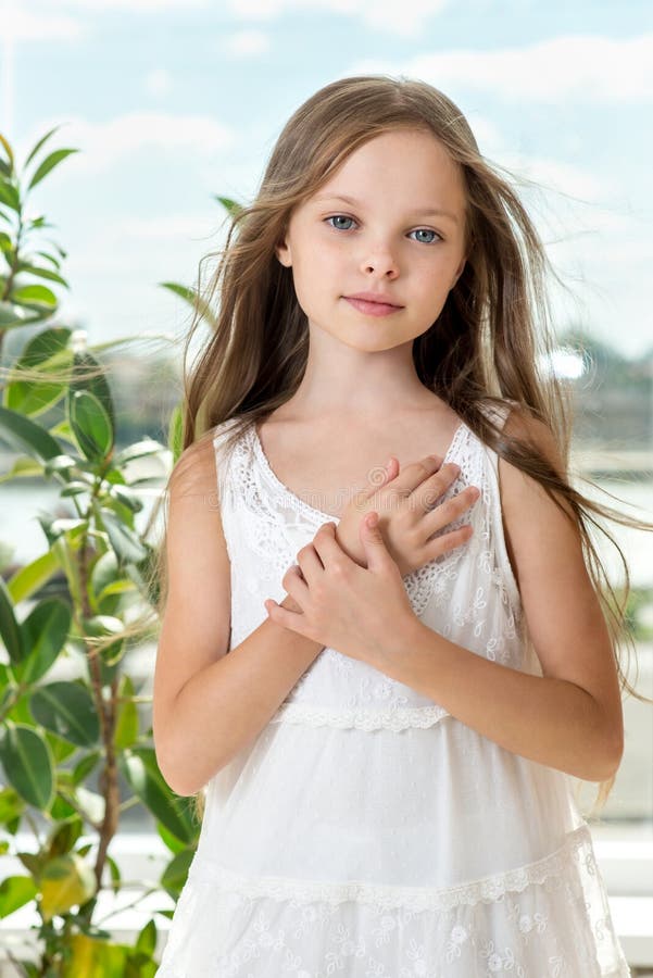 Portret pięknej uśmiechniętej dziewczynki z długą, zdrową fryzurą przed oknem fotografia stock