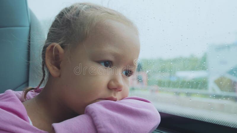 Portret przyglądający smutny dziecko out mokry okno, podczas gdy podróżujący autobusem