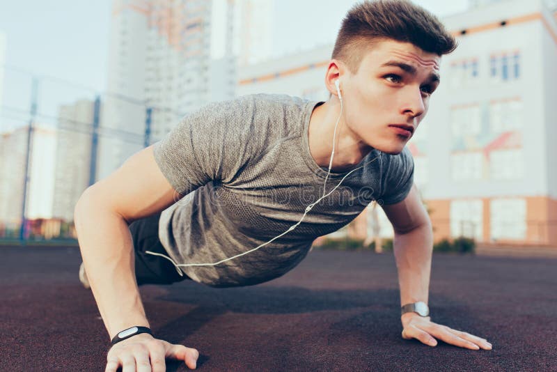 Portret przystojny facet z dobrym ciałem przy sportem w ranku na stadium Jest ubranym sport odziewa, słuchający muzyka zdjęcie stock Portret przystojny facet z dobrym ciałem przy sportem w ranku na stadium Jest ubranym sport odziewa, słuchający muzyka zdjęcie stock