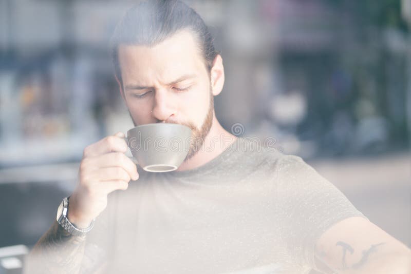 Portret przystojny modnisia mężczyzna z brodą cieszy się filiżanka kawy relaksującego obsiadanie na krześle przy kawiarnią obrazy stock Portret przystojny modnisia mężczyzna z brodą cieszy się filiżanka kawy relaksującego obsiadanie na krześle przy kawiarnią obrazy stock