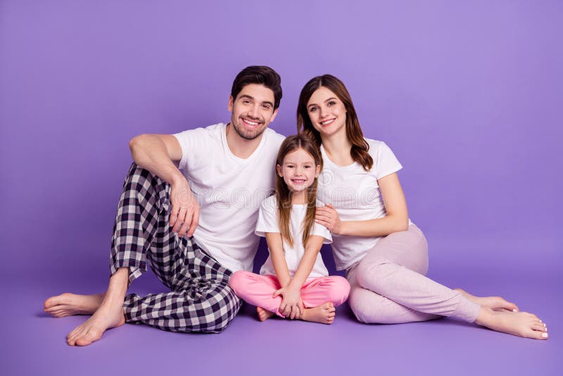 Portret radosnego ojca rodzinnego, matki, córki potomka w przytulnej piżamie siedzącej na podłodze i siedzącej w domu