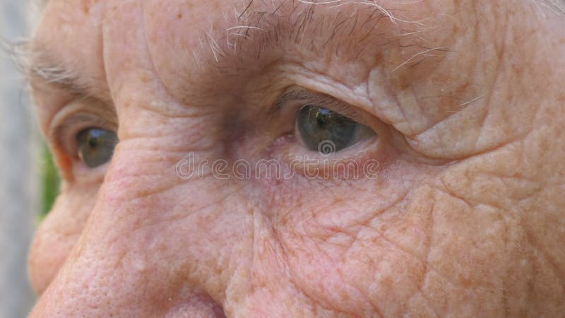 Portret starszej babci patrzy w dal smutnym wzrokiem. zbliżyć szare oczy dojrzałej kobiety ze zmarszczeniami wokół