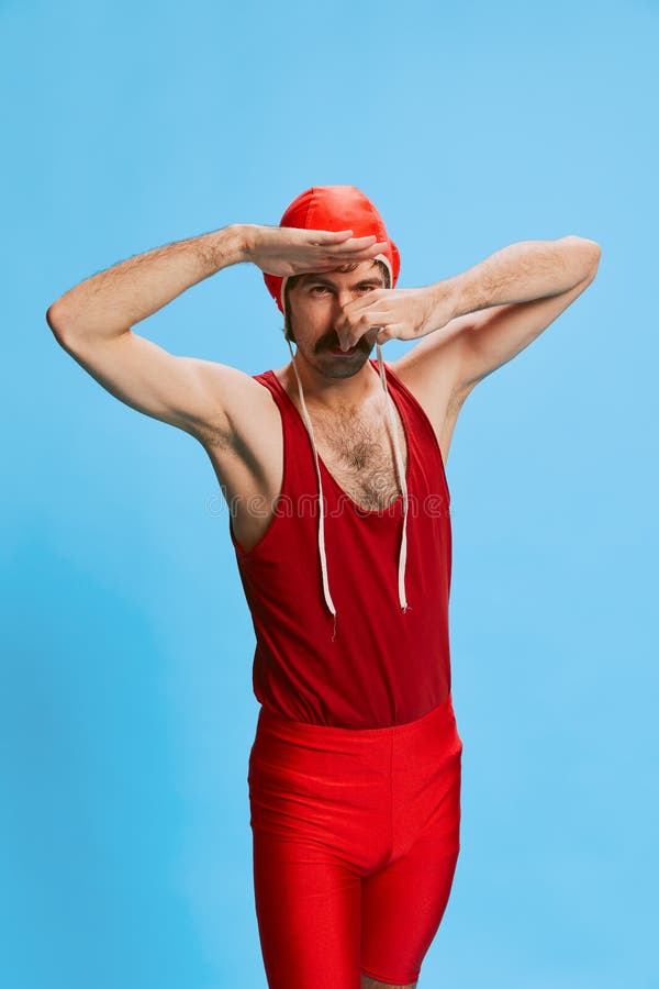 Portret stylowego mężczyzny z wąsami pozującymi się w wielowarstwowym stroju kąpielowym, pokrywającego nos przed skokiem wyizolowa fotografia royalty free