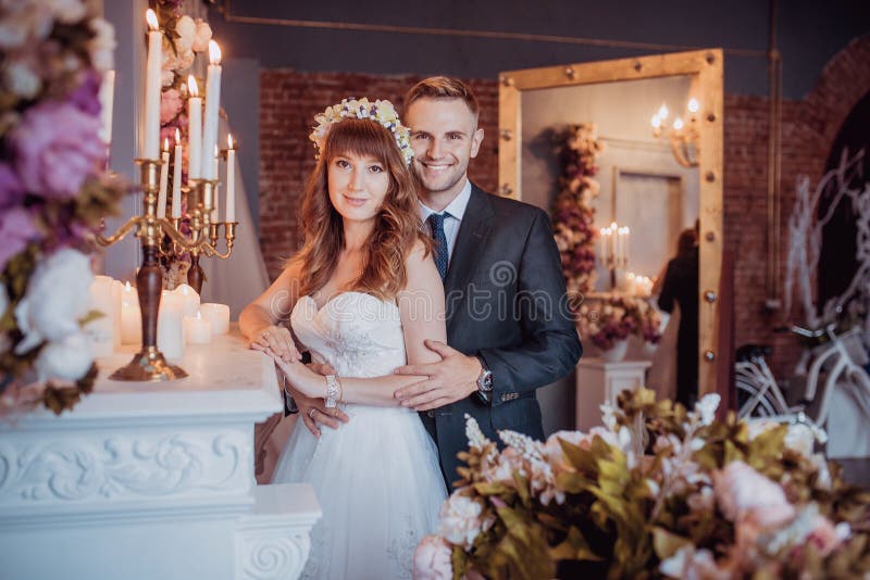 Portret szczęśliwy młody państwo młodzi w klasycznym wnętrzu blisko graby z kwiatami Dzień ślubu, miłość temat dzień pierwszy fotografia stock Portret szczęśliwy młody państwo młodzi w klasycznym wnętrzu blisko graby z kwiatami Dzień ślubu, miłość temat dzień pierwszy fotografia stock