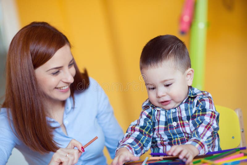 Portret szczęśliwa ładna matka z jej berbecia syna rysunkiem fotografia stock Portret szczęśliwa ładna matka z jej berbecia syna rysunkiem fotografia stock