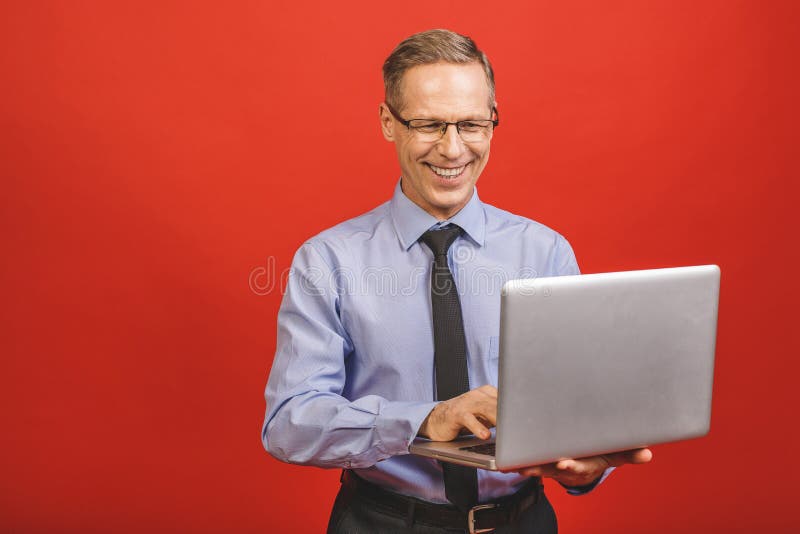 Portret szczęśliwego starszego biznesmena trzymającego notebooka na czerwonym tle zdjęcia stock