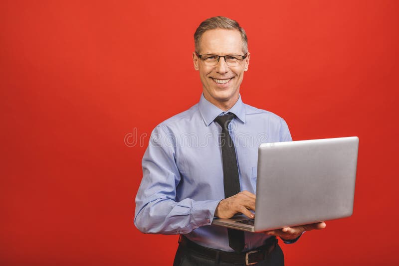 Portret szczęśliwego starszego biznesmena trzymającego notebooka na czerwonym tle zdjęcie stock
