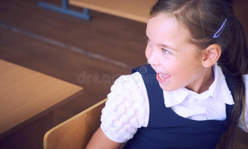 Portret szczęśliwy młodej dziewczyny obsiadanie przy stołem w szkole podstawowej W górę twarzy uśmiechnięta Latynoska uczennica obrazy royalty free Portret szczęśliwy młodej dziewczyny obsiadanie przy stołem w szkole podstawowej W górę twarzy uśmiechnięta Latynoska uczennica obrazy royalty free
