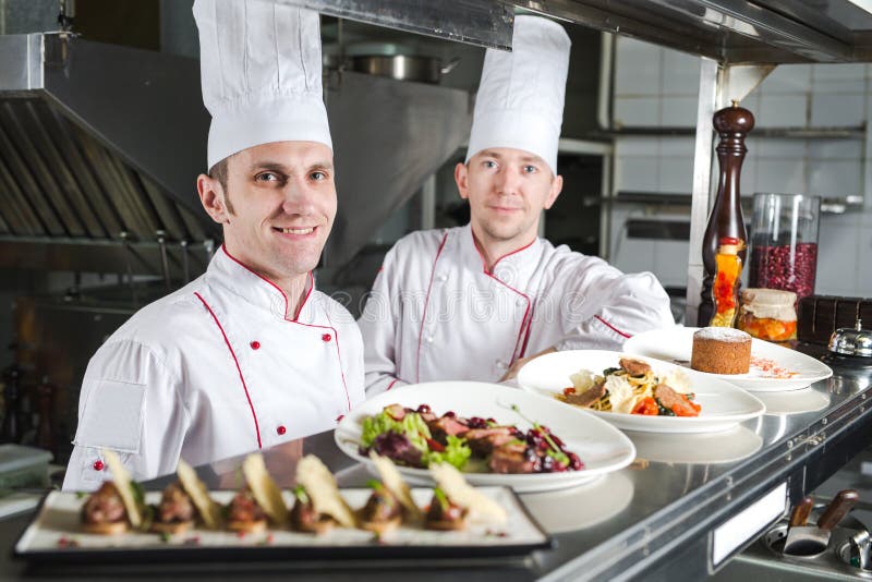Portret szef kuchni z gotującym jedzeniem w kuchni w restauracji obraz stock Portret szef kuchni z gotującym jedzeniem w kuchni w restauracji obraz stock