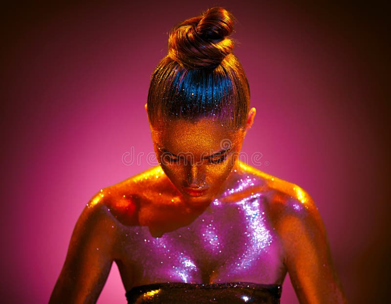 Portret sztuki mody. modelka dziewczyna w kolorowych jasnych błyszczących złoto i różowa skóra neon światła pozujące w studio pięk