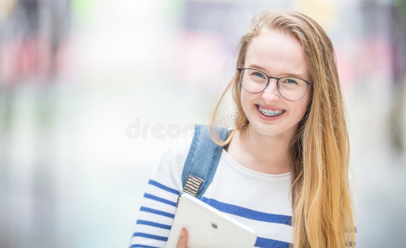 Portret uśmiechnięta piękna nastoletnia dziewczyna z stomatologicznymi brasami Młoda uczennica z szkolnej torby i pastylki pr obrazy stock Portret uśmiechnięta piękna nastoletnia dziewczyna z stomatologicznymi brasami Młoda uczennica z szkolnej torby i pastylki pr obrazy stock
