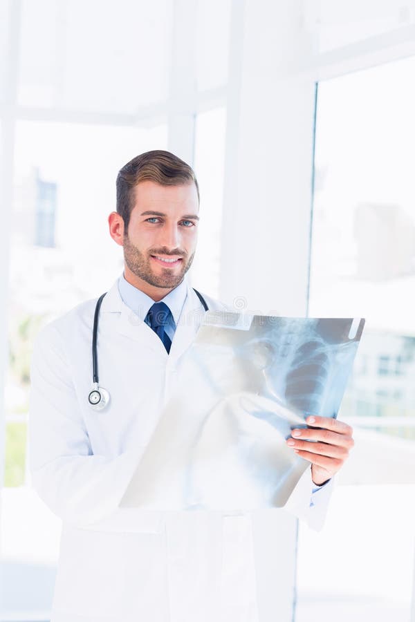 Portret uśmiechniętej młodej samiec doktorski egzamininuje xray zdjęcia royalty free Portret uśmiechniętej młodej samiec doktorski egzamininuje xray zdjęcia royalty free