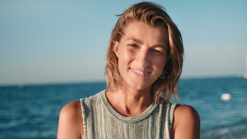Portret van aangename jonge blonde vrouw met gelooide huid glimlachend op zonsondergang