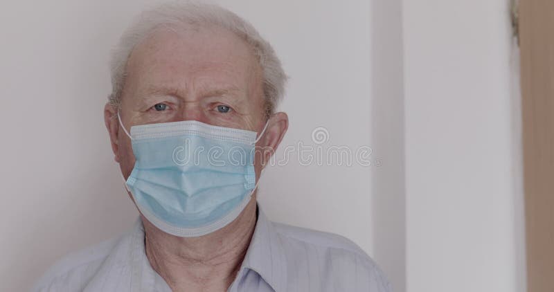 Portret van bedachtzame grootvader in masker op gezicht, die helaas naar camera kijkt