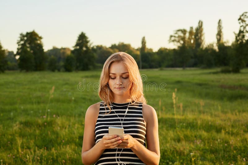 Portret van blond meisje met haar mobiele telefoon en oortelefoons royalty-vrije stock afbeeldingen Portret van blond meisje met haar mobiele telefoon en oortelefoons royalty-vrije stock afbeeldingen