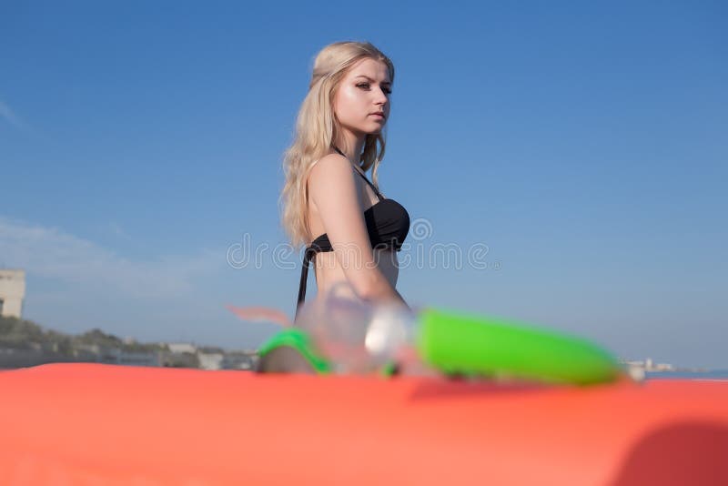 Portret van blondemeisje in zwarte bikini tegen de hemel stock foto Portret van blondemeisje in zwarte bikini tegen de hemel stock foto