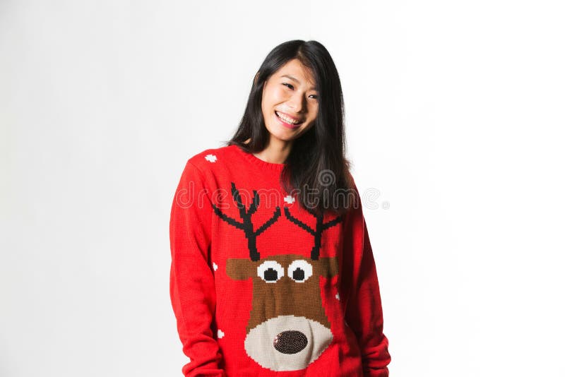 Portret van Chinese vrouw in Kerstmissweater die zich voor grijze achtergrond bevinden stock foto's Portret van Chinese vrouw in Kerstmissweater die zich voor grijze achtergrond bevinden stock foto's