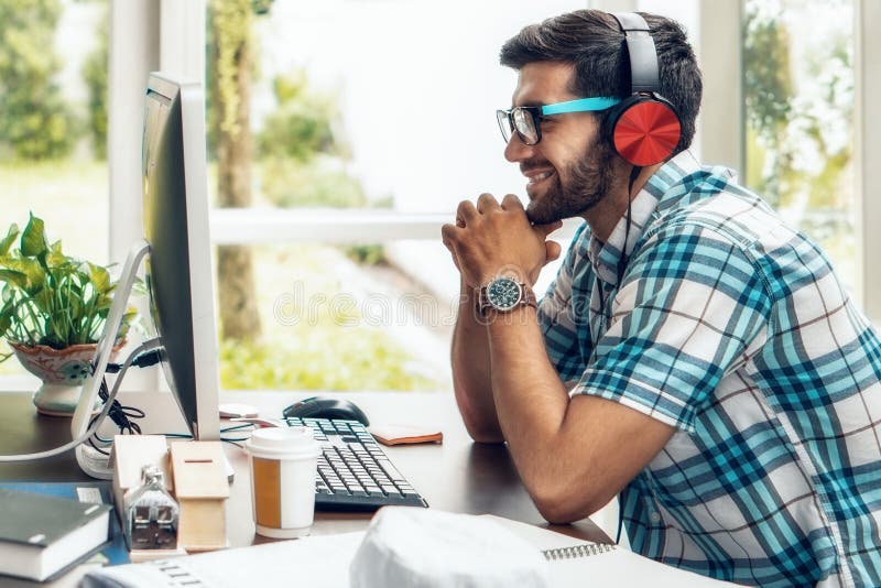 Portret van de caucasiaanse zakenman die aan het werk zit met computer glimlachen en naar muziek luisteren met een headset op het