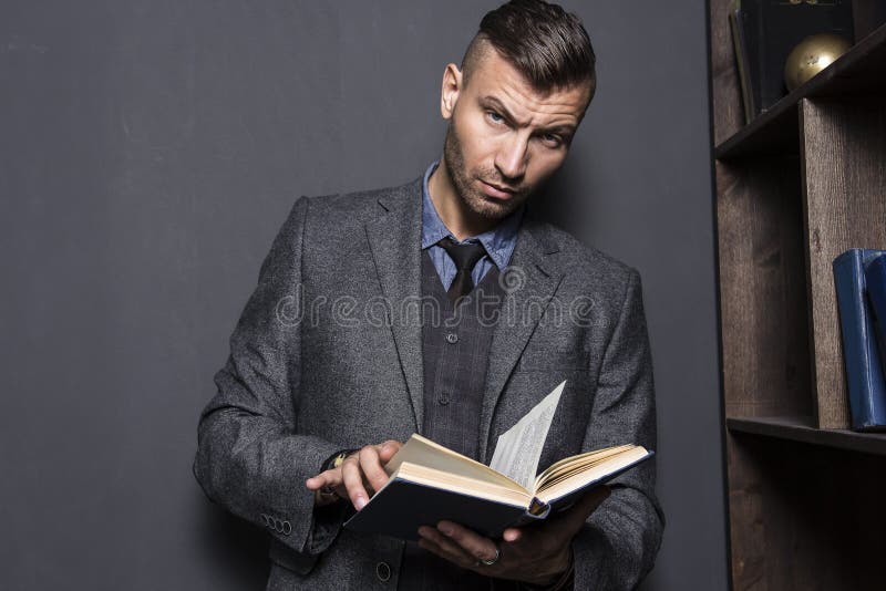 Portret van de modieuze, elegante jonge mens in kostuum met boek De jonge knappe mens leest boek stock foto Portret van de modieuze, elegante jonge mens in kostuum met boek De jonge knappe mens leest boek stock foto