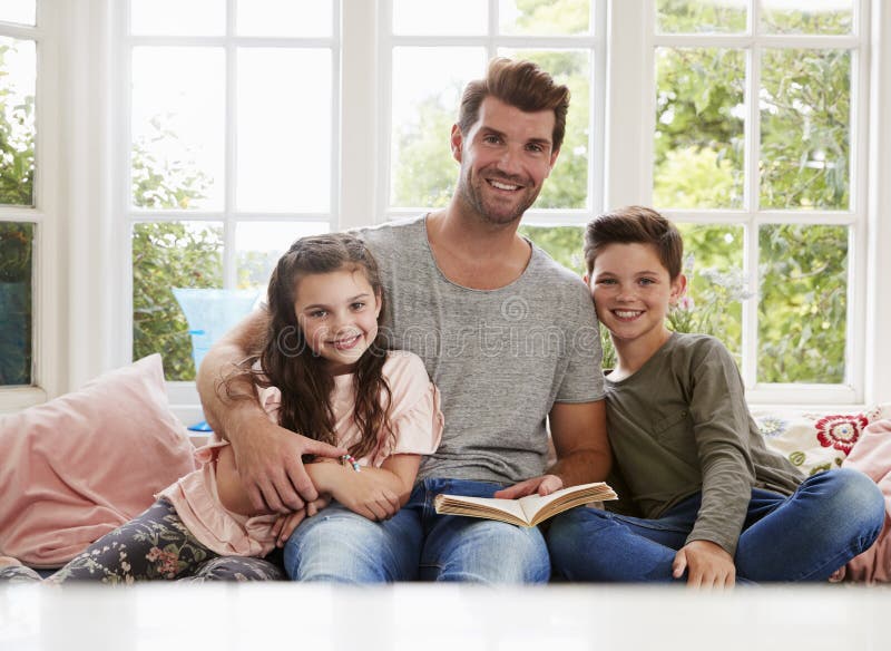 Portret van de Zoon en de Dochter van Vaderreading book with thuis royalty-vrije stock afbeeldingen Portret van de Zoon en de Dochter van Vaderreading book with thuis royalty-vrije stock afbeeldingen