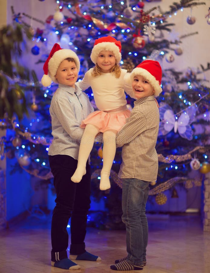 Portret van drie gelukkige kinderen die pret hebben bij Kerstmisvooravond royalty-vrije stock foto Portret van drie gelukkige kinderen die pret hebben bij Kerstmisvooravond royalty-vrije stock foto