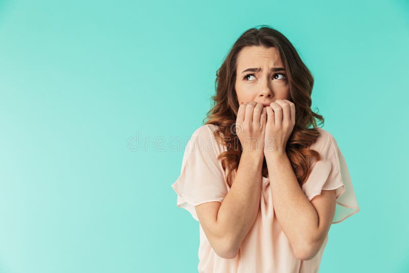 Portrait of a frightened young girl in dress looking away at copy space isolated over blue background. Portrait of a frightened young girl in dress looking away at copy space isolated over blue background