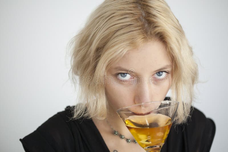 Drinkt de Jonge Vrouw van de blonde met Mooie Blauwe Ogen een Martini stock fotografie Drinkt de Jonge Vrouw van de blonde met Mooie Blauwe Ogen een Martini stock fotografie
