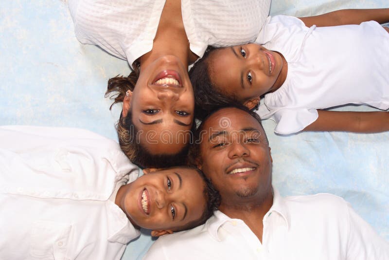 A portrait of a diverse family of four laying on the floor, picture taken from above. A portrait of a diverse family of four laying on the floor, picture taken from above.