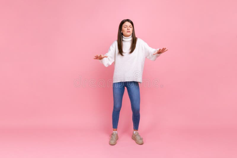 Full length portrait of disoriented girl walks with eyes closed, holding out her hands to find road, wearing white casual style sweater. Indoor studio shot isolated on pink background. Full length portrait of disoriented girl walks with eyes closed, holding out her hands to find road, wearing white casual style sweater. Indoor studio shot isolated on pink background.