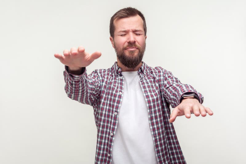 Portrait of disoriented bearded man in plaid shirt standing with closed eyes and outstretched arms searching lost road, eyesight problems, blindness. indoor studio shot isolated on white background. Portrait of disoriented bearded man in plaid shirt standing with closed eyes and outstretched arms searching lost road, eyesight problems, blindness. indoor studio shot isolated on white background