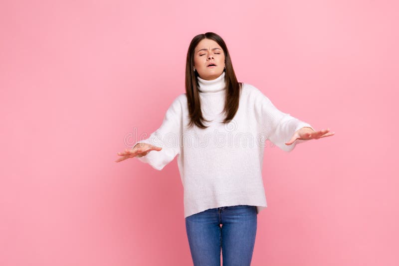 Portrait of disoriented young woman walking with eyes closed and holding out her hands to find road, wearing white casual style sweater. Indoor studio shot isolated on pink background. Portrait of disoriented young woman walking with eyes closed and holding out her hands to find road, wearing white casual style sweater. Indoor studio shot isolated on pink background.