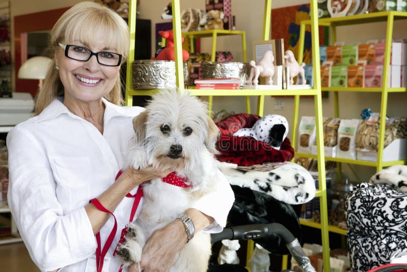 Portret van een gelukkige hogere vrouwen dragende hond in dierenwinkel stock afbeeldingen Portret van een gelukkige hogere vrouwen dragende hond in dierenwinkel stock afbeeldingen