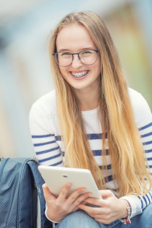 Portret van een glimlachende mooie tiener met tandsteunen Jong schoolmeisje met schooltas en tabletapparaat royalty-vrije stock foto Portret van een glimlachende mooie tiener met tandsteunen Jong schoolmeisje met schooltas en tabletapparaat royalty-vrije stock foto