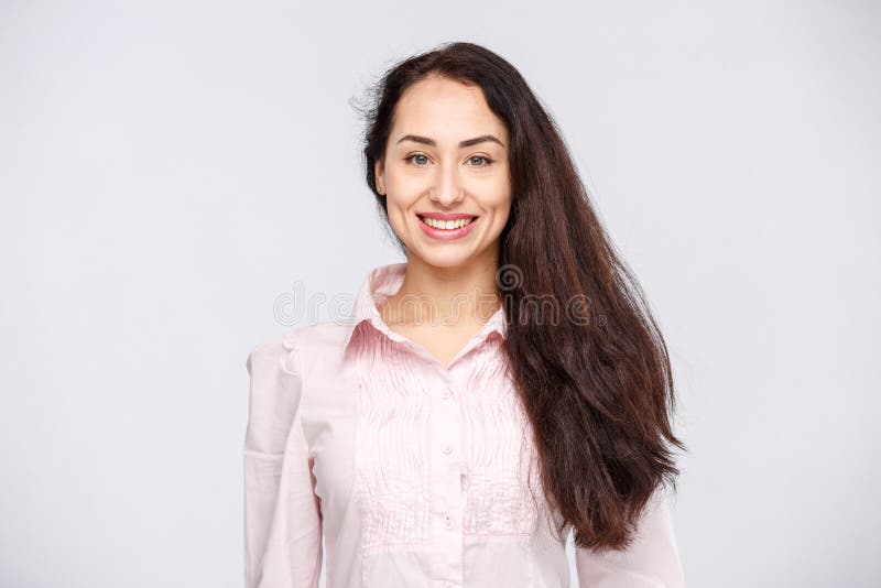 Portret van een jonge vrouw met een charmante toothy glimlach, een zwart haar en bruine ogen op een witte achtergrond in een roze stock afbeeldingen Portret van een jonge vrouw met een charmante toothy glimlach, een zwart haar en bruine ogen op een witte achtergrond in een roze stock afbeeldingen
