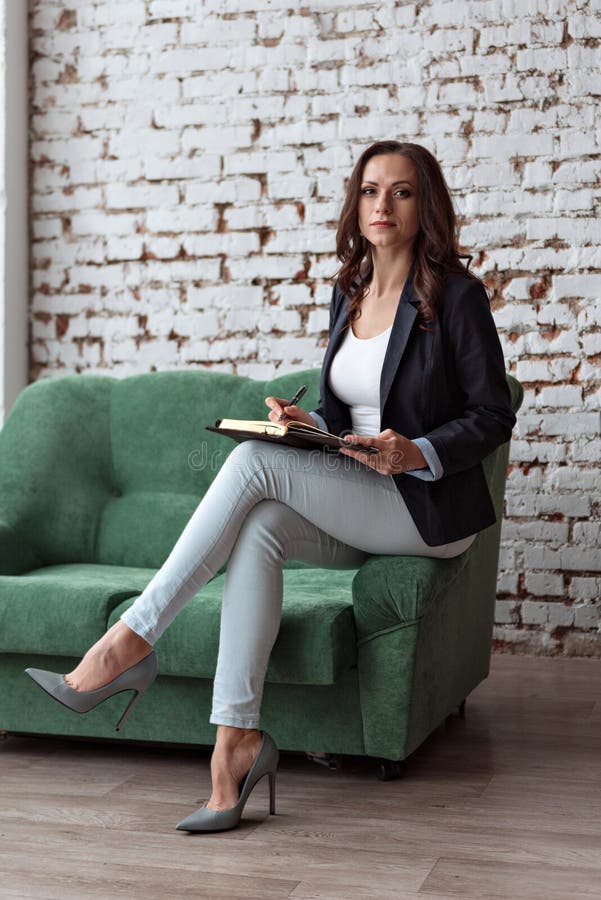 Portret van een jonge vrouwen bedrijfsbuszitting op de bankplank die een notitieboekje houden kijkend recht stock afbeelding Portret van een jonge vrouwen bedrijfsbuszitting op de bankplank die een notitieboekje houden kijkend recht stock afbeelding