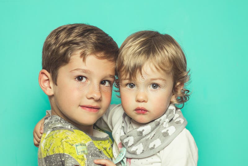 Portret van een kleine jongen en een weinig een klein meisje die de camera met een lichte glimlach bekijken royalty-vrije stock fotografie Portret van een kleine jongen en een weinig een klein meisje die de camera met een lichte glimlach bekijken royalty-vrije stock fotografie